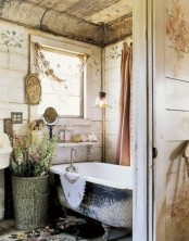 a shabby chic bathroom with shiplap walls, mirrors, a clawfoot tub, florla rugs and a basket with blooms