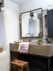 a wabi-sabi bathroom with a concrete sink, a large mirror, a wooden stool, bright towels and dinosaurs