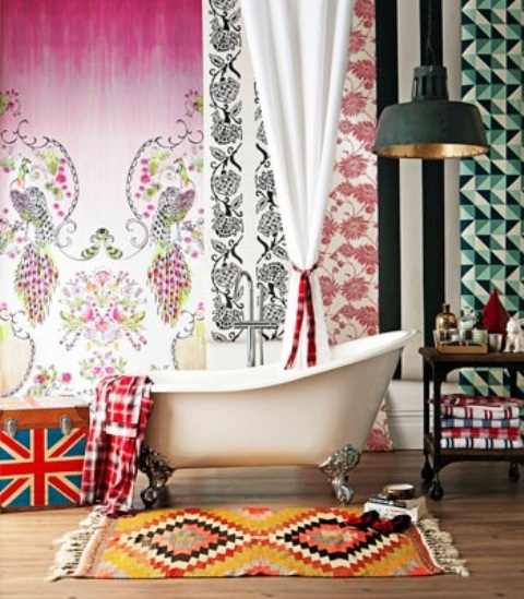 a bright eclectic bathroom with boho curtains and a rug, an industrial lamp and a clawfoot tub