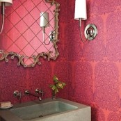 a bright pink and purple patterned space with a concrete sink and a gorgeous ornate mirror