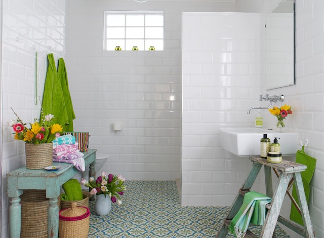 a neutral bathroom with a bright mosaic tile floor, shabby chic wooden furniture in pastel colors and potted blooms