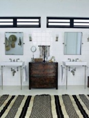 a monochromatic bathroom with a striped rug, a dark stained dresser and straw hats