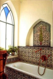 a bright Moroccan space with Moroccan tiles, a mosaic window, potted greenery and dark copper hardware