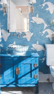 a blue bathroom with fish print wallpaper, a bright blue vanity, a painted vessel sink and a chic mirror