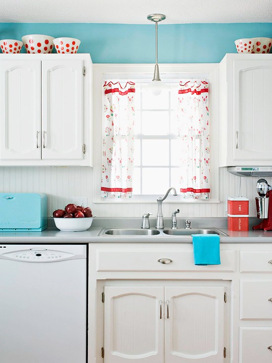 a bright blue kitchen with white cabinetry, bold blue accessories and printed red touches is a vivacious space