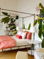 a tropical bedroom done with an elegant framed bed, a statement wallpaper wall and peachy pink beddinh
