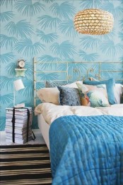 blue tropical print wallpaper, a wicker lamp and a forged bed for a stylish and chic modern tropical space