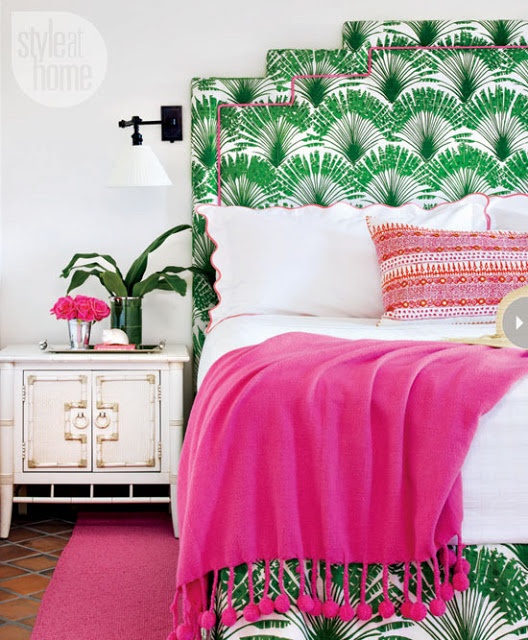 a bright tropical bed, a printed pillow, a hot pink blanket and a white colonial-style nightstand