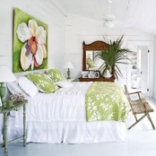 a whitewashed bedroom with bright pistachio green touches, palm leaves, a shabby chic bench and a statement artwork