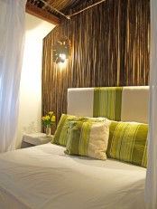 a real bamboo statement wall, bright green stripes, a wood slice wall lamp for a tropical touch