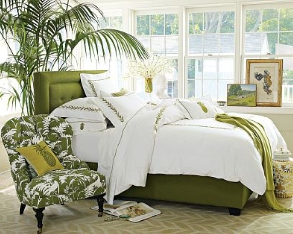 bright green touches, a potted palm tree, a grene printed chair make the bedroom feel tropical