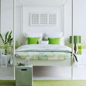 a bright white and green bedroom with patterns on the wall and bedding, a green lamp and pillows