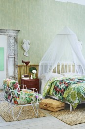 green printed wallpaper, bright tropical print textiles, wicker rugs and a bamboo wall make the bedroom feel tropical