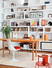 a welcoming and light-filled home office with a whole wall of built-in shelves and some furniture is a cool space to work