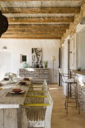 a rustic dining room with a wooden ceiling and beams, a whitewashed sideboard, a whitewashed dining table and chairs