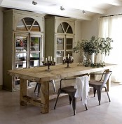 an elegant rustic dining room with a stained table, metal chairs, whitewashed buffets and potted greenery is a welcoming and lovely space