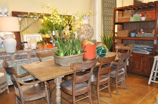 a rustic dining room with a stained storage unit, a relcaimed wood dresser, a stained table and chairs, bold blooms and a large mirror