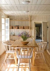 a neutral rustic dining room filled with natural light, with a stained table and chairs, open shelves for storage and displaying and blooms