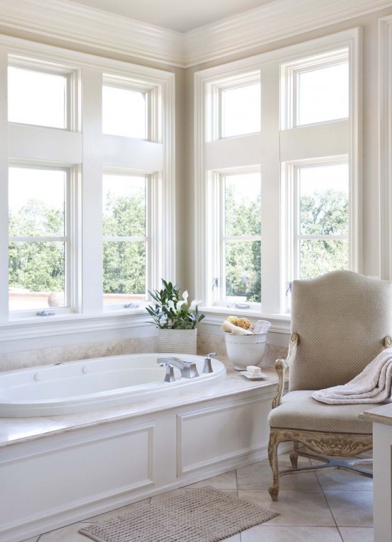 a neutral refined bathroom with a tub clad with panels, a refined vintage chair and  some blooms is a very beautiful and peaceful idea