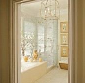 a neutral bathroom with a built-in tub clad with marble, a shower space, a gallery wall and a vintage chandelier