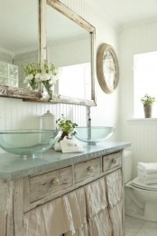 a neutral shabby chic bathroom with a vanity, glass sinks, a double mirror and white beadboard walls