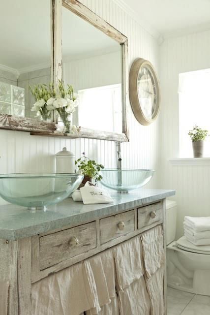 a neutral shabby chic bathroom with a vanity, glass sinks, a double mirror and white beadboard walls