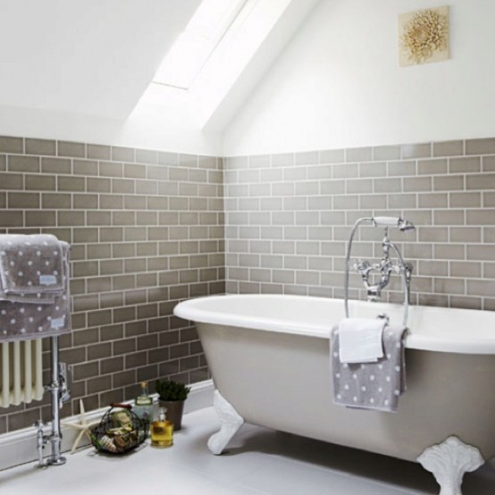a lovely neutral bathroom with grey subway tiles, a grey clawfoot bathtub and polka dot towels is a cozy and refined space