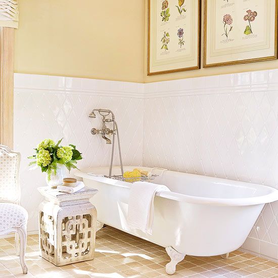 a cozy vintage bathroom with a tile backsplash, a vintage poster gallery wall, a clawfoot tub and a carved side table