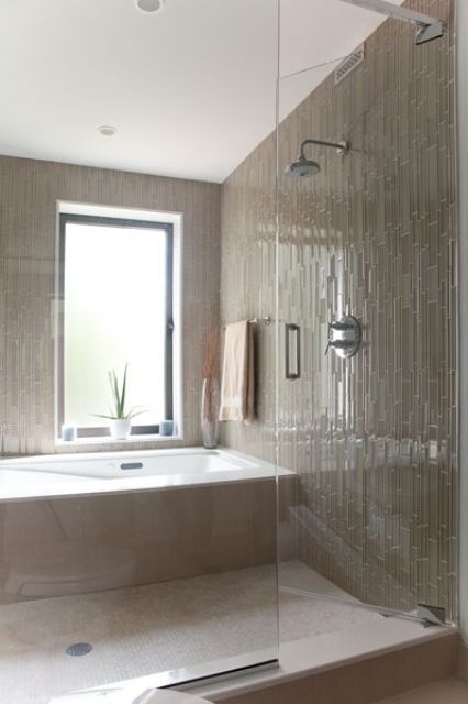 a tan bathroom clad with skinny tiles, a bathtub clad with tiles, too, and a window with frosted glass is amazing