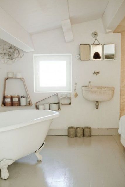 a neutral and industrial vintage bathroom with a clawfoot tub, open shelves, mirrors and a wall-mounted sink