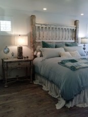 a shabby chic bedroom with a shabby whitewashed bed, blue bedding, whitewashed nightstands, a driftwood table lamp and built-in lights