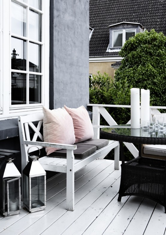a laconic Scandinavian terrace with a white planked bench with pastel pillows, a black round table and some candle lanterns is a lovely idea a laconic Scandinavian terrace with a white planked bench with pastel pillows, a black round table and some candle lanterns is a lovely idea