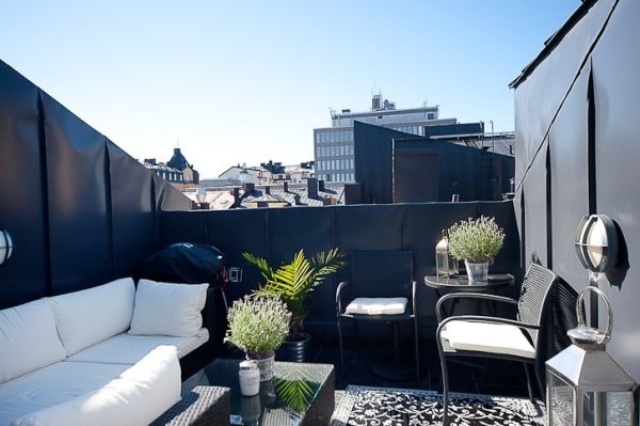 a black and white Nordic terrace with a white sofa and chairs, a black coffee table and potted greenery