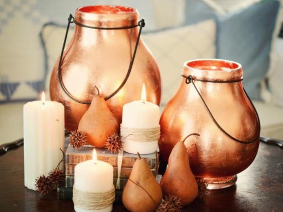 a cozy and pretty Thanksgiving centerpiece of pears, pillar candles, copper candle lanterns and soem dried seed pods is amazing