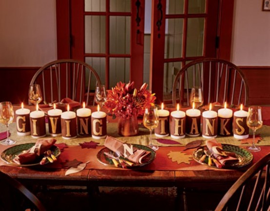 candles wrapped with letters and a copper vase with red blooms are perfect for an easy and bold Thanksgiving centerpiece