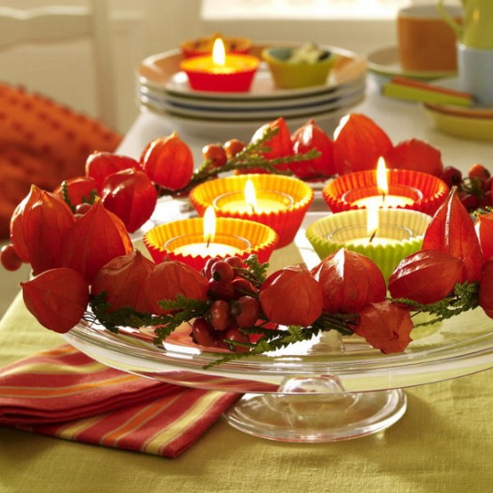 a beautiful Thanksgiving centerpiece of seed pods, greenery, berries and candles in colorful cupcake liners