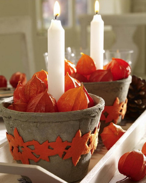 concrete planters with orange clay leaves, seed pods and tall and thin candles are amazing for styling your space for Thanksgiving