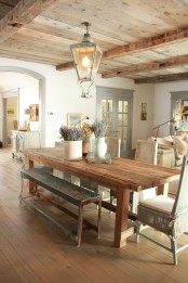 a welcoming and cozy Provence dining room with a stained dining table, mismatcing chairs, a wooden ceiling with a lantern and lavender in jugs