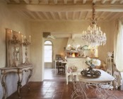 a refined French chic dining room with neutral walls, an oval table and vintage chairs, a crystal chandelier, a console table and a mirror, tall vintage candelabras