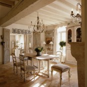 a neutral Provence dining room with a vintage creamy buffet, a folding table and refined vintage chairs, chandeliers and some artwork