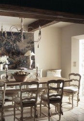 a sophisticated Provence dining room with dark wooden beams, a stained table and refined neutral chairs, a console table and a large artwork is wow