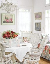 a white vintage sunroom with white wicker furniture, floral textiles, floral artworks and a chic white chandelier