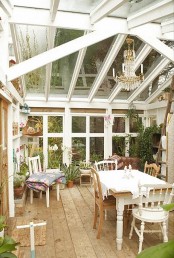 a chic vintage sunroom with vintage painted and stained furniture, a crystal chandelier, potted greenery and blooms and floral textiles