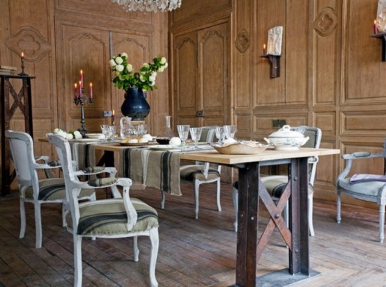 a French country dining room with wooden paneled walls, a table and chic vintage chairs, a crystal chandelier and some neutral blooms