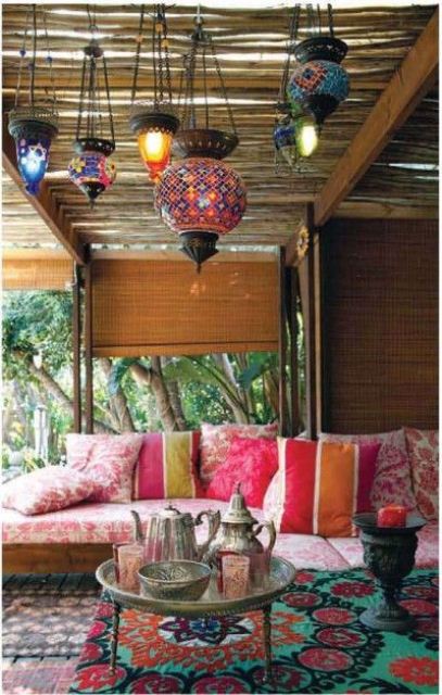 a colorful Moroccan patio with lots of bright mosaic lanterns, a printed pink sofa, a low coffee table with coffeeware