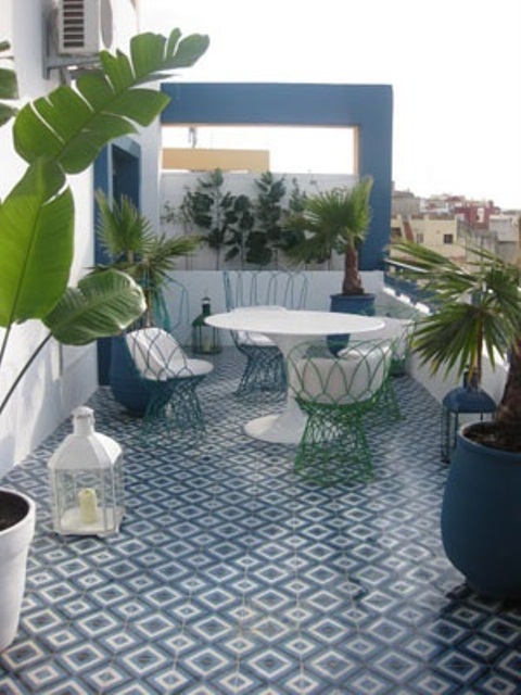 a blue Moroccan patio with a tiled floor, potted greenery and blue and white furniture