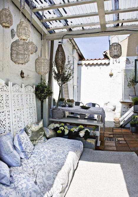 a neutral Moroccan patio done with touches of blue, low furniture and rattan lanterns over the space