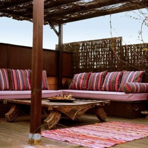 a pink Moroccan patio with striped textiles, a low coffee table and striped pillows