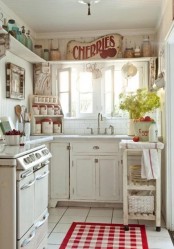a white shabby chic kitchen with vintage cabinets and shelves, a printed rug, bright signs and greenery plus red touches