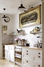 a neutral retro kitchen with white cabinets, butcher block countertops, a neutral tiel backsplash and black retro lamps over the space